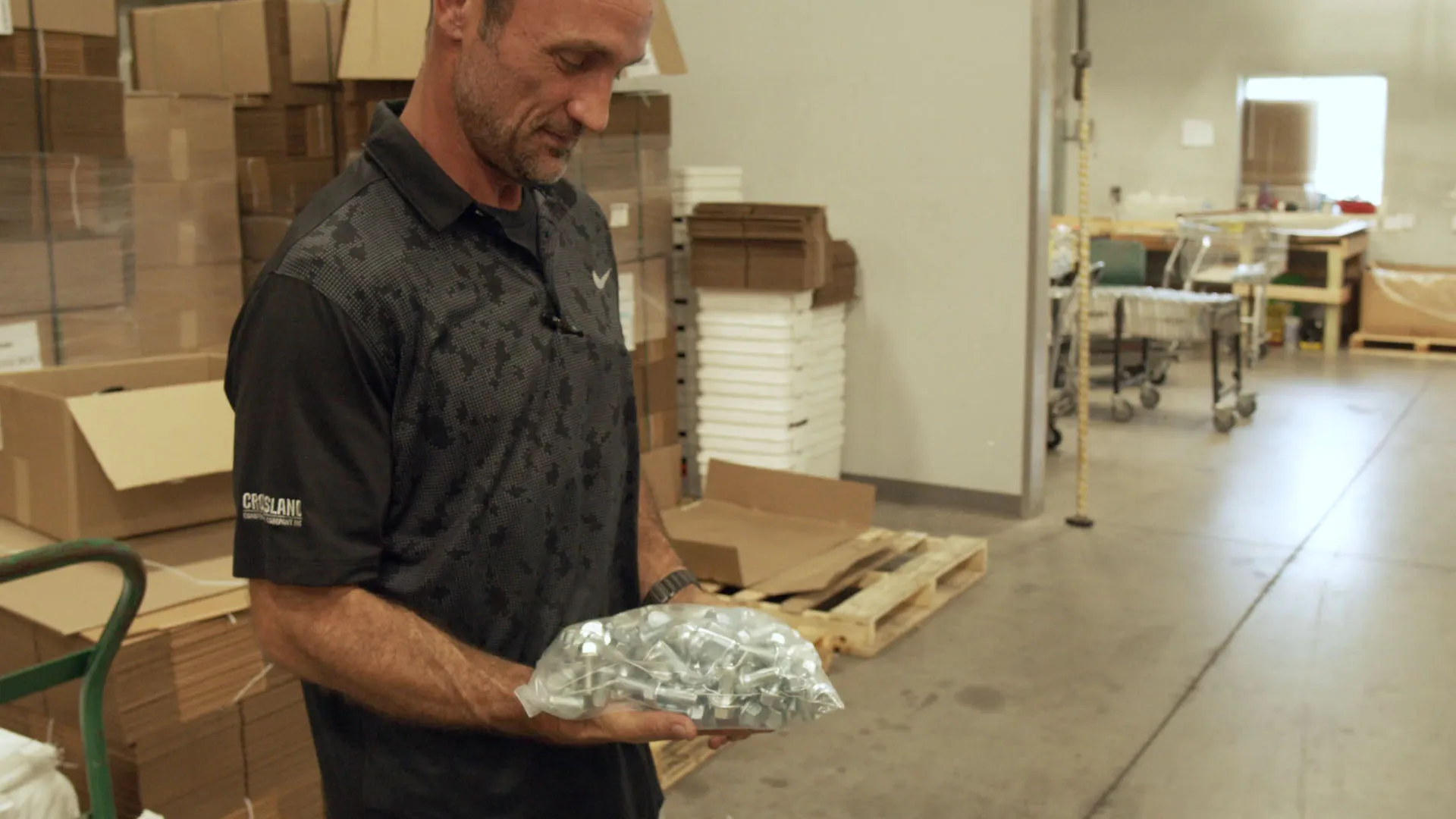 Nick holding a bag of packaged metal fasteners in the Component Packaging warehouse