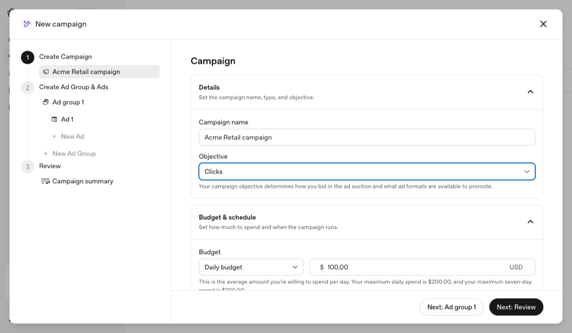 The campaign creation wizard with the Objective dropdown open, showing three options: Reach, Clicks and Conversions. Below it, the daily budget field and its spend cap explanation.