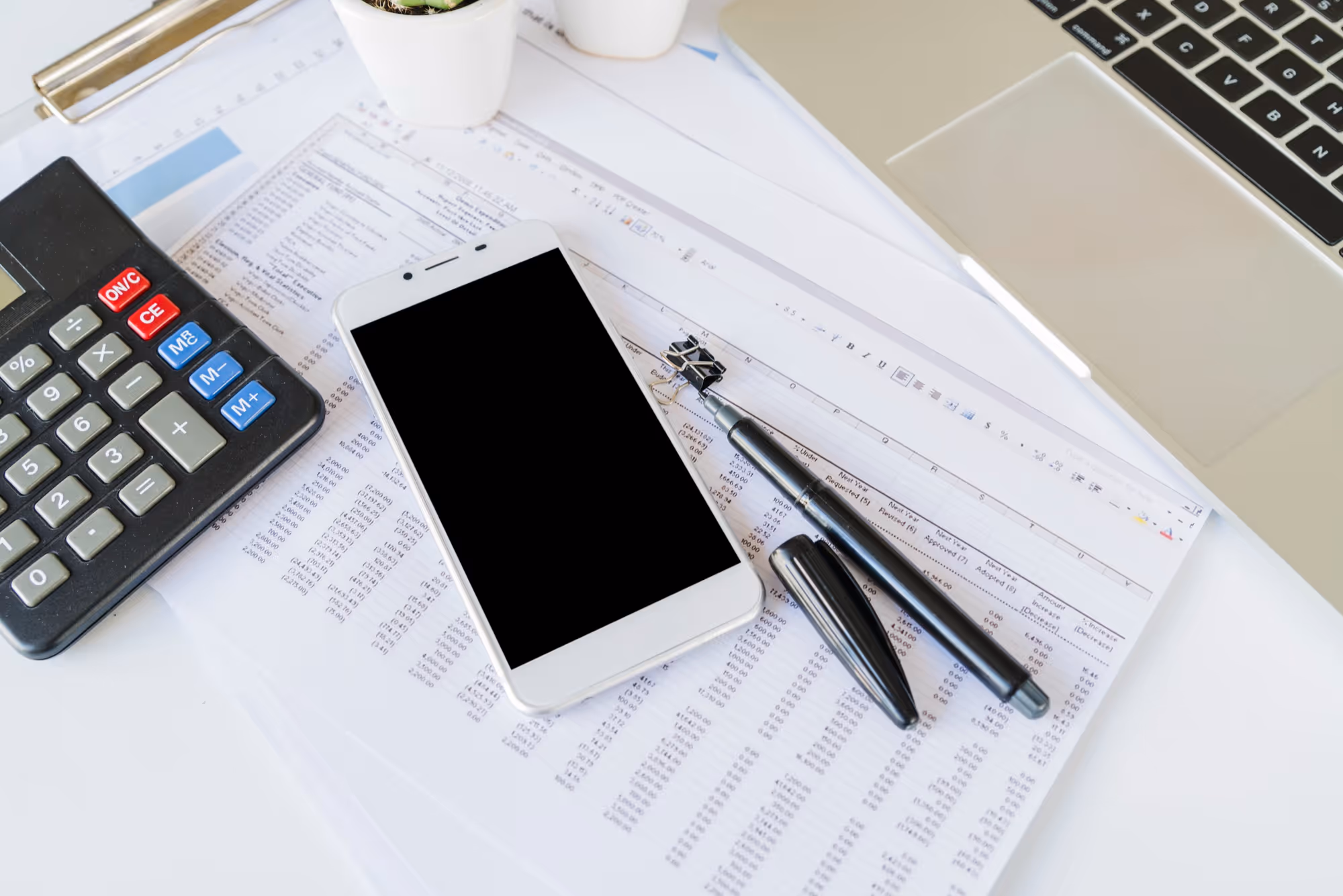 Table with phone, laptop, calculator and printed paper of an excel file