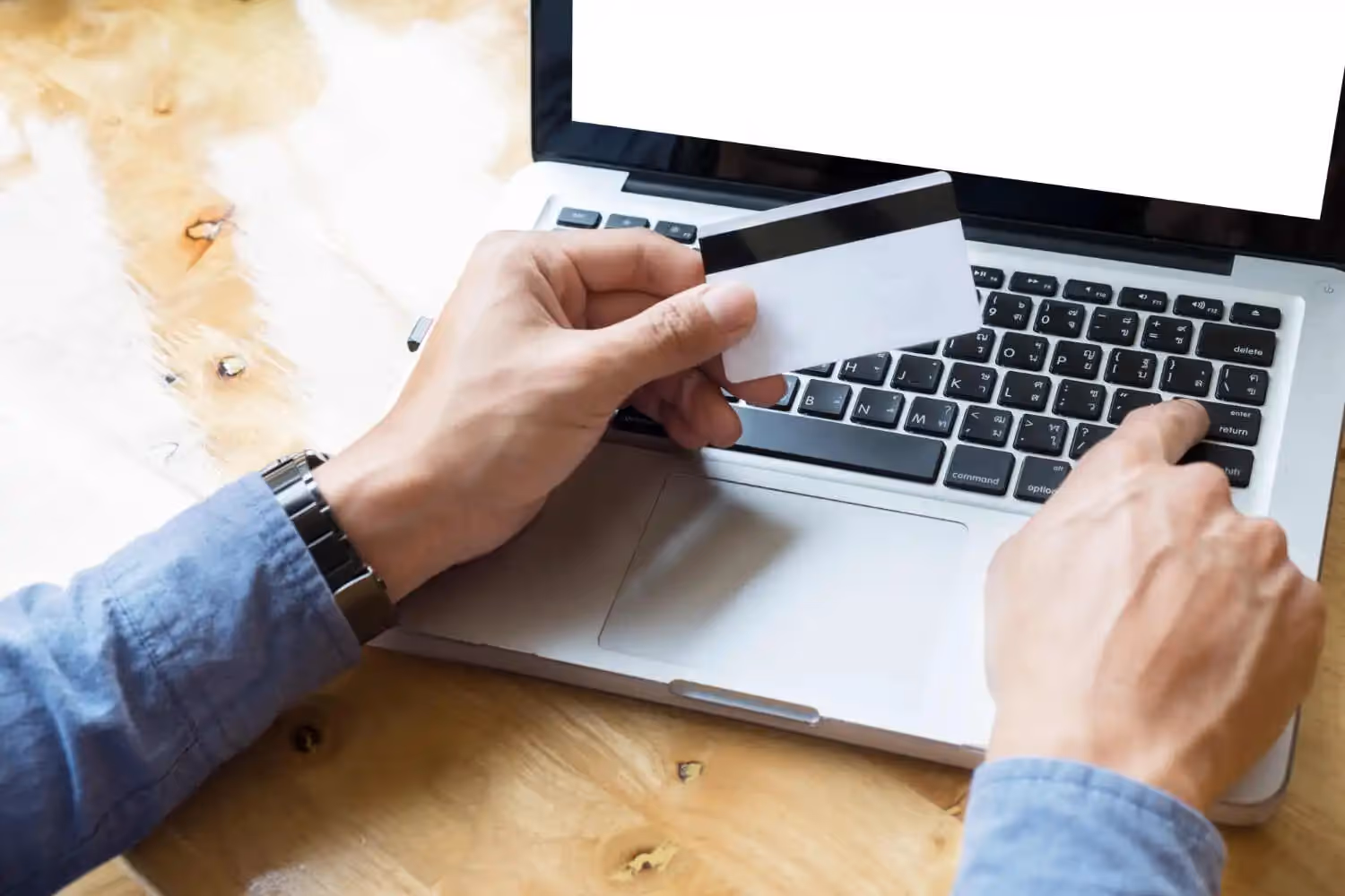 link building employee holding credit card in front of a laptop