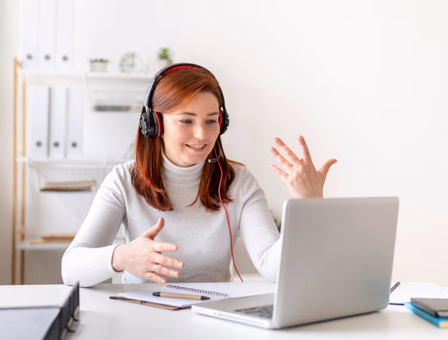 Woman wearing headphones, talking and explaining in front of computer