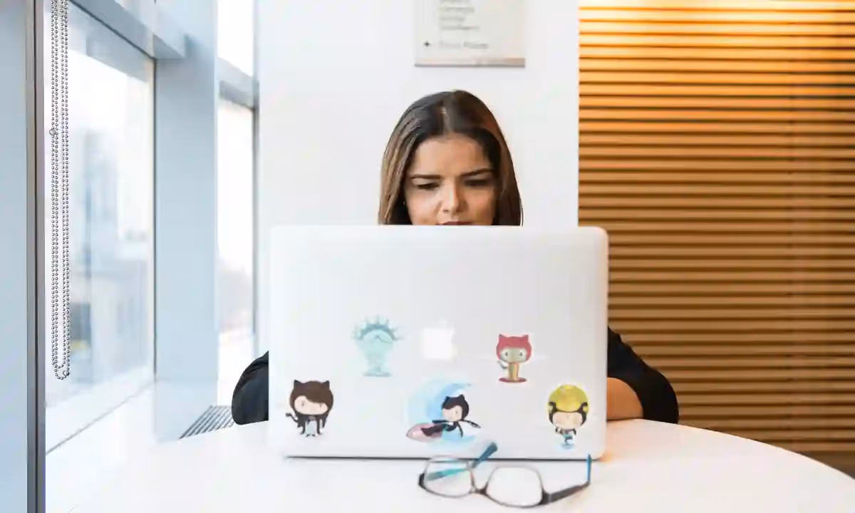 Woman in focus working on software development remotely on laptop indoors.