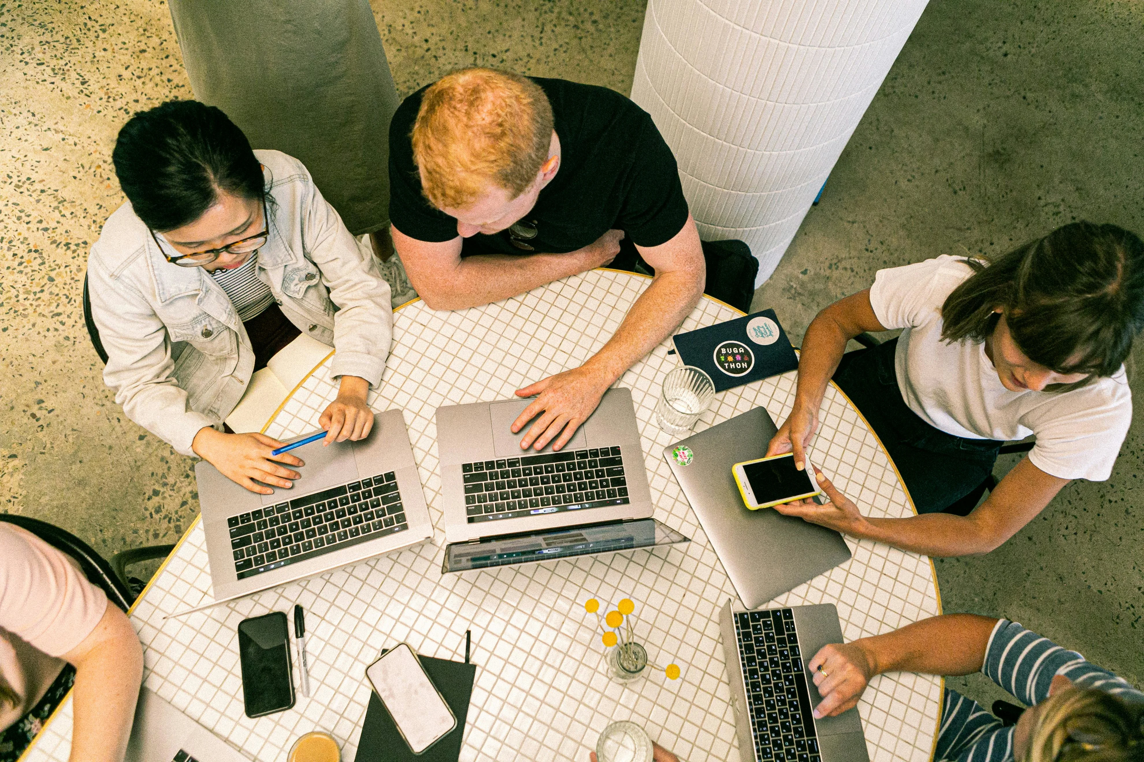 Table from above with people working on their computers.