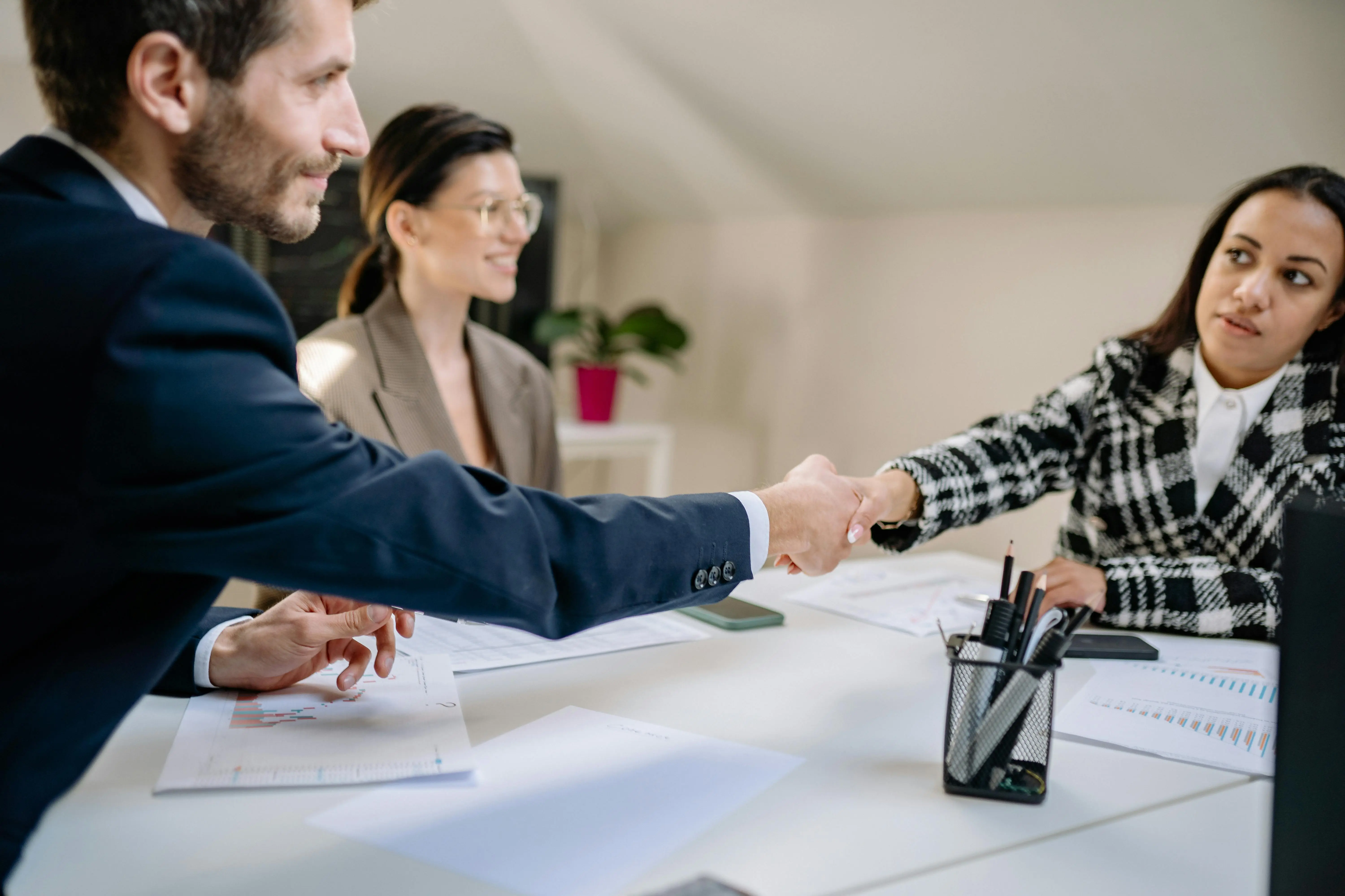 Man and woman shaking hands on a meeting table.