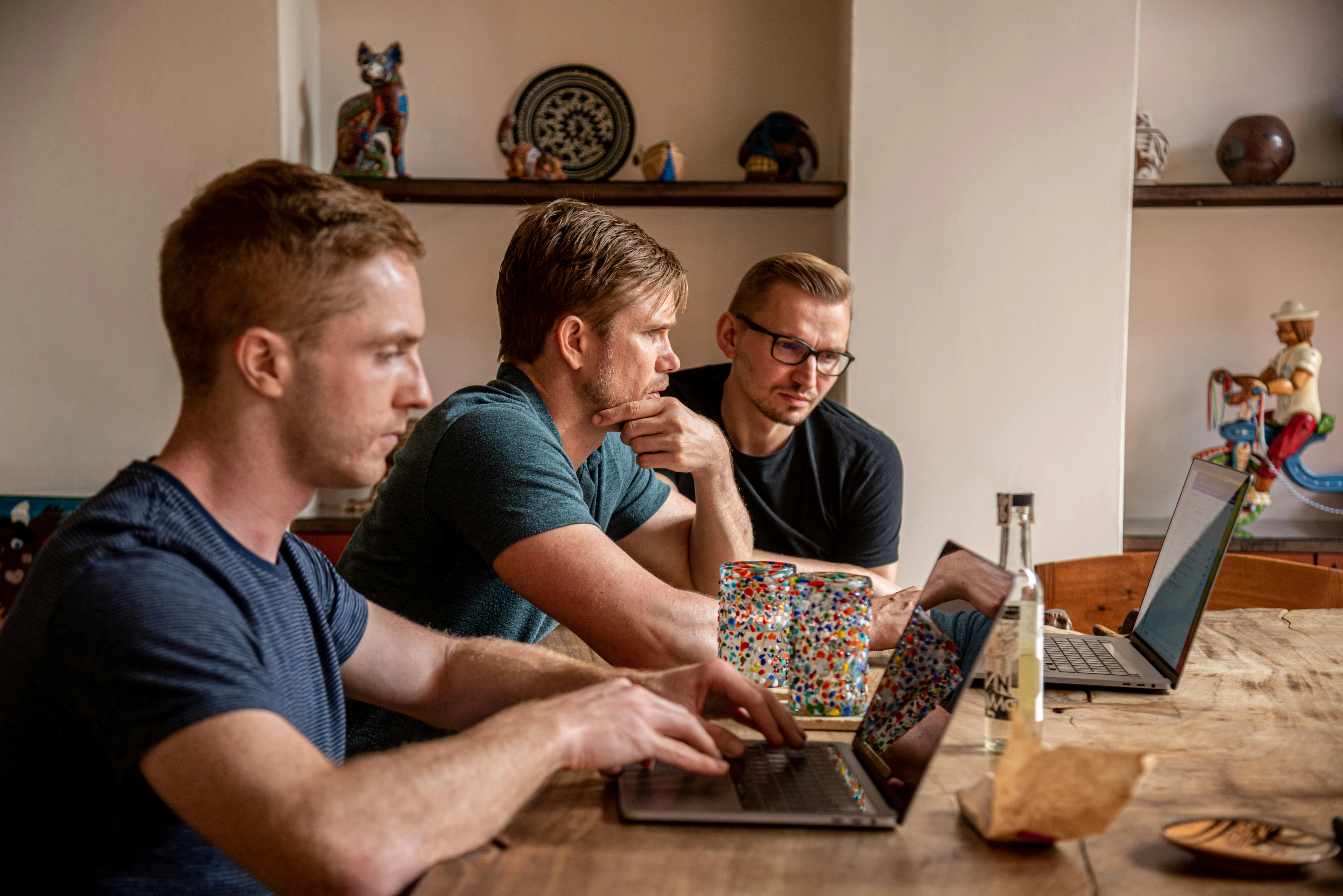 Group of men working on their computers on a table.