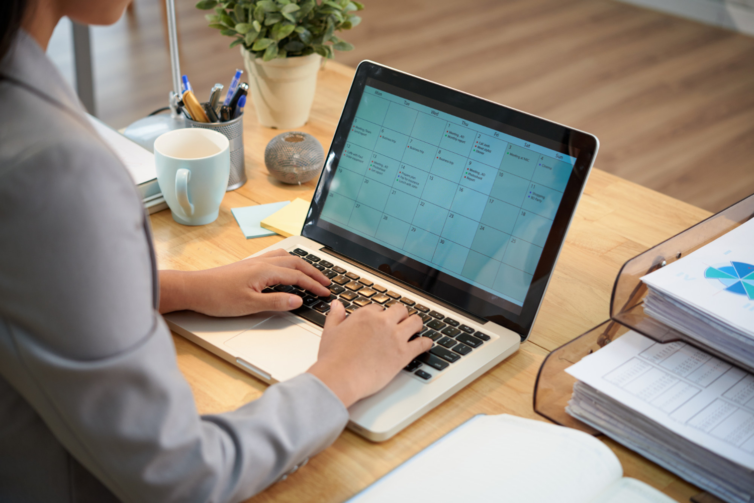 Woman working on laptop, laptop showing calendar with tasks