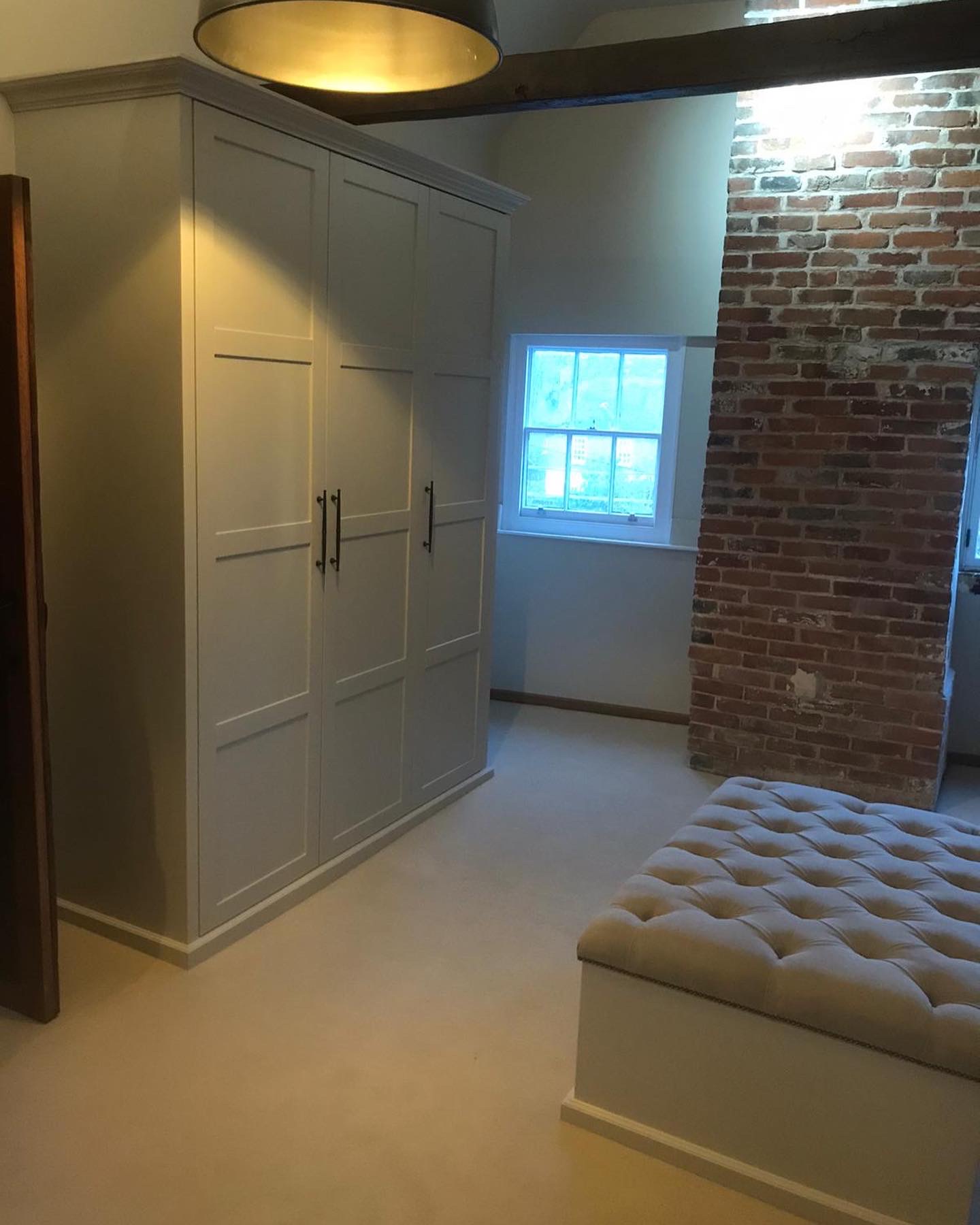 A room with a wardrobe and a brick wall.