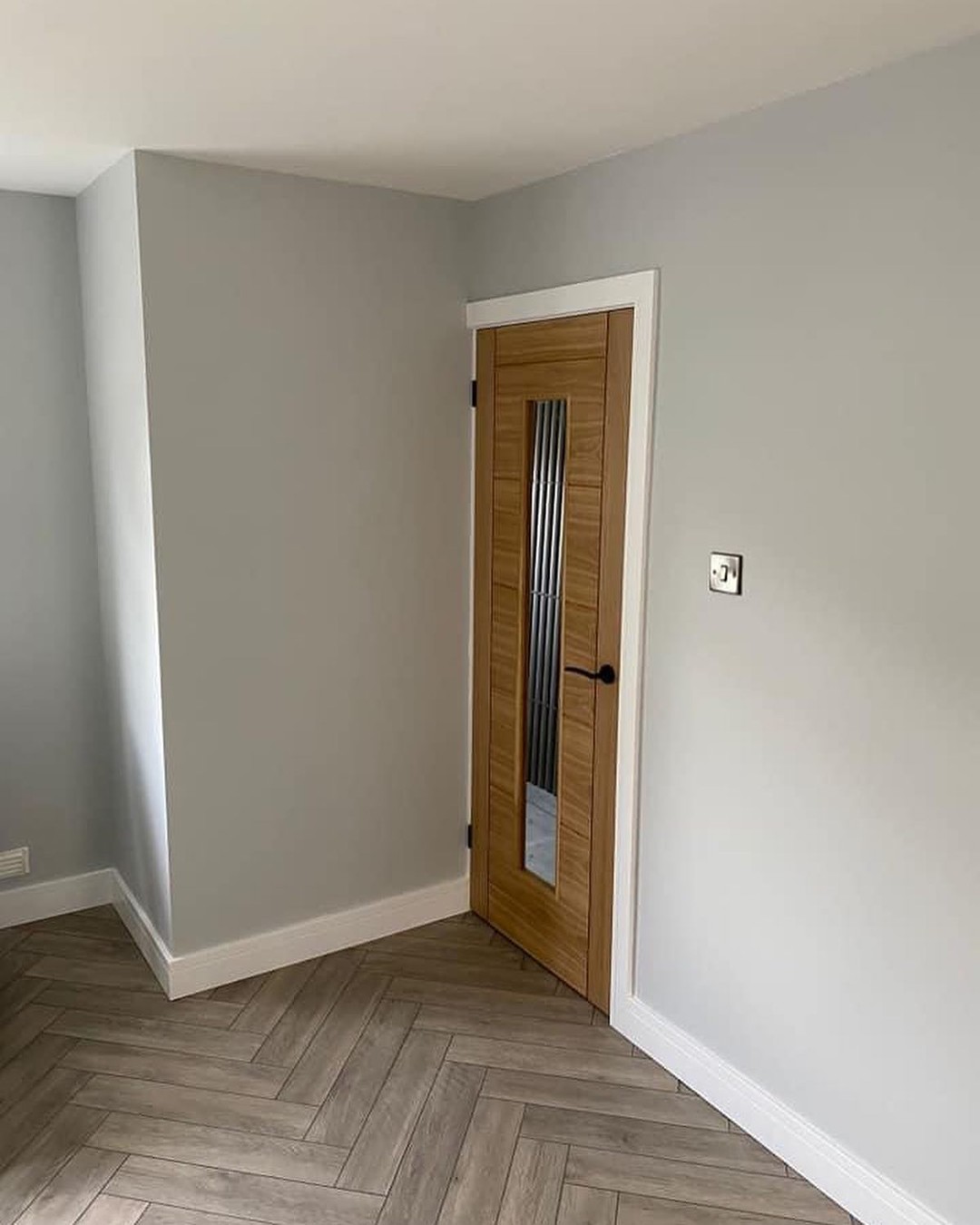 An empty room with a wooden door and hard wood floor.