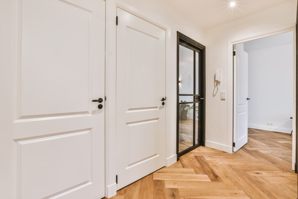A white room with two doors and a wooden floor.
