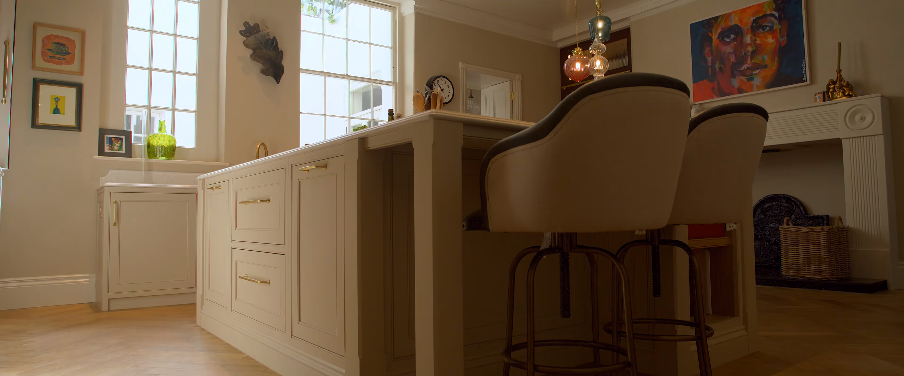 A modern kitchen with a white island, bar stools, and large windows letting in natural light.