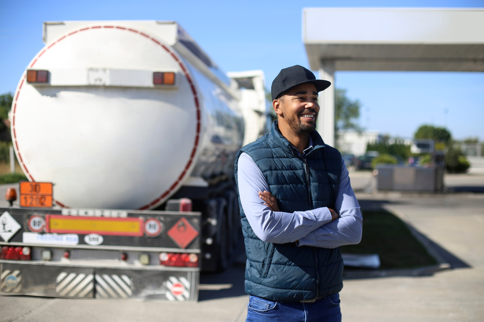 A trucking employee stands in front of his vehicle at a gas station