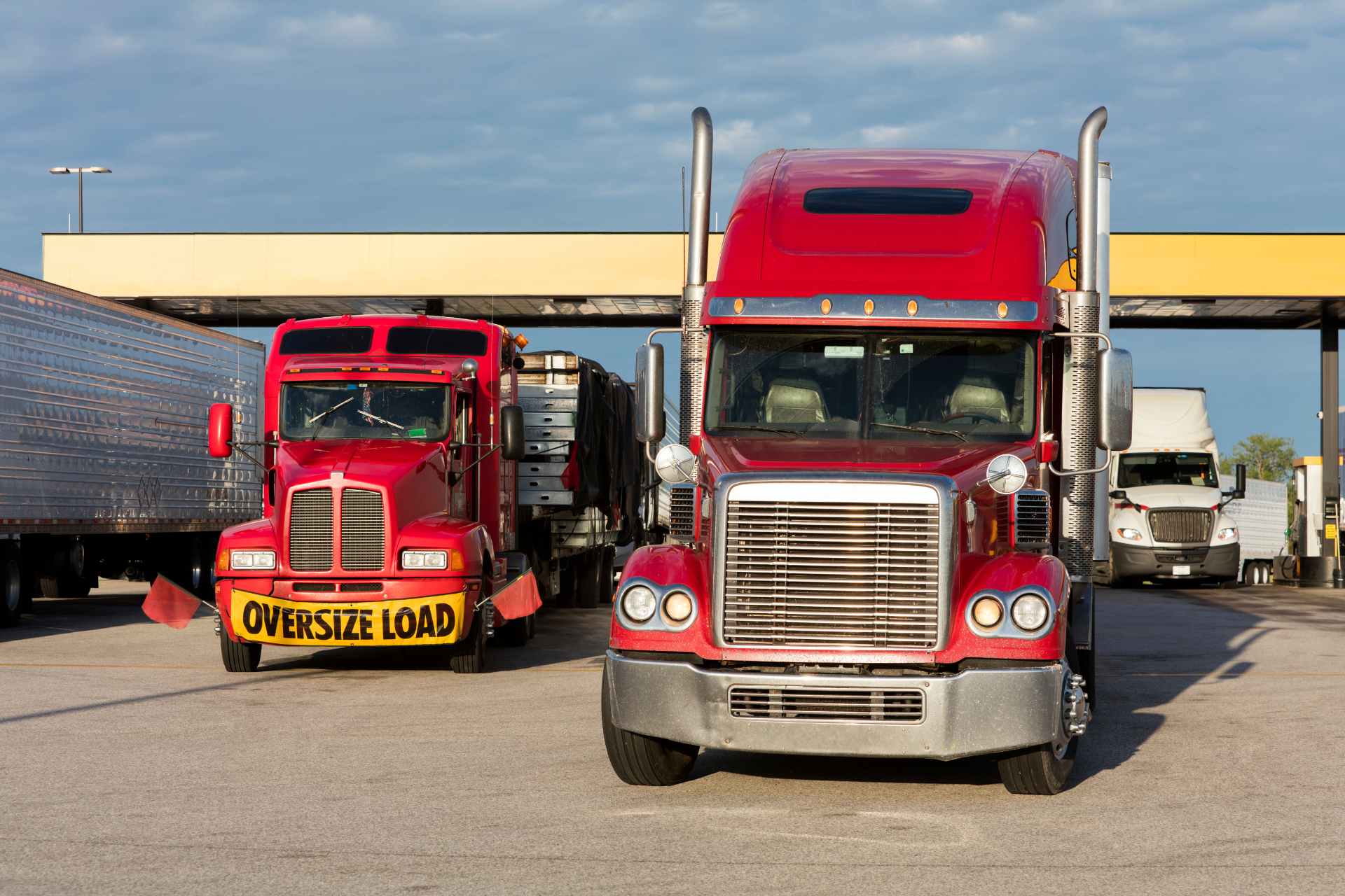 two red cargo trucks at a gas station