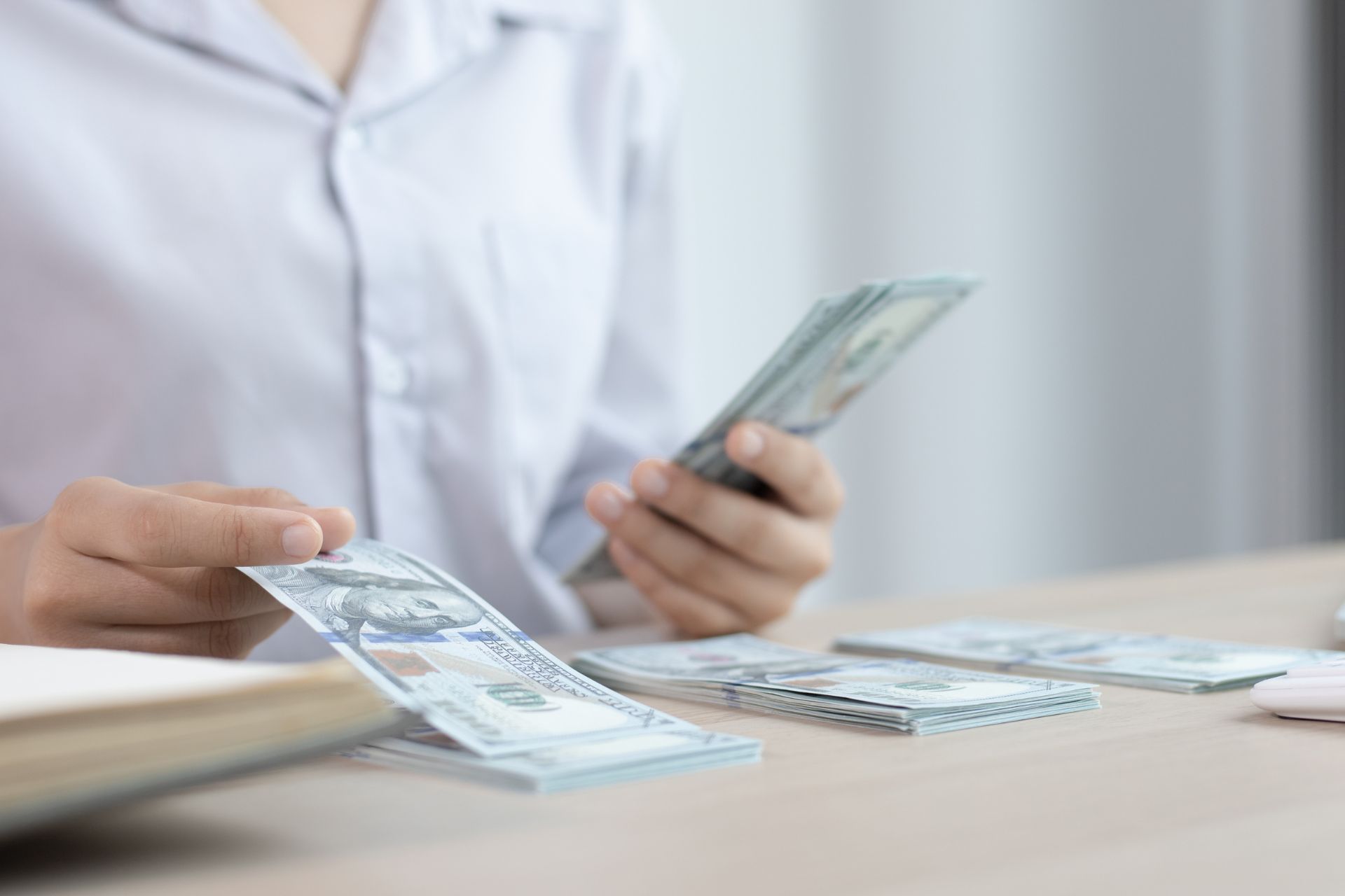 A small business owner counts stacks of $100 bills
