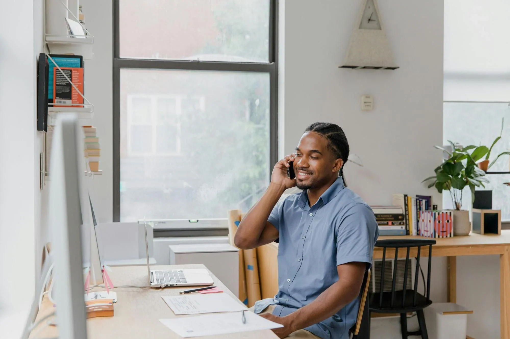 Confident business owner smiling while on the phone with laptop open, representing success after securing funding