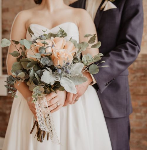 Husband and wife in embrace with flower bouquet.