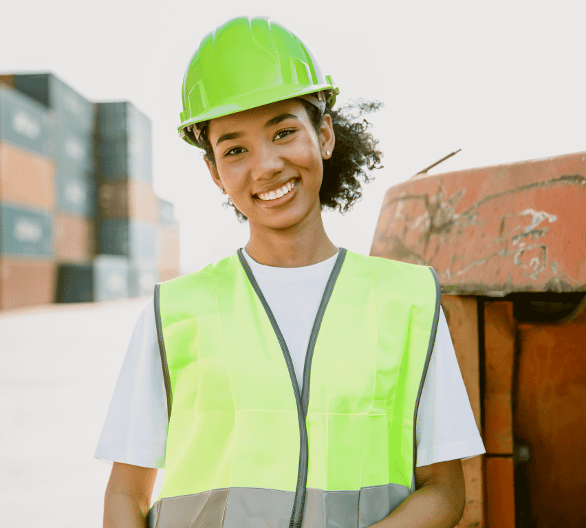 Female multi-site facility worker in hi-vis vest and hard hat at a container yard, keeping multiple sites in sync with Goramp