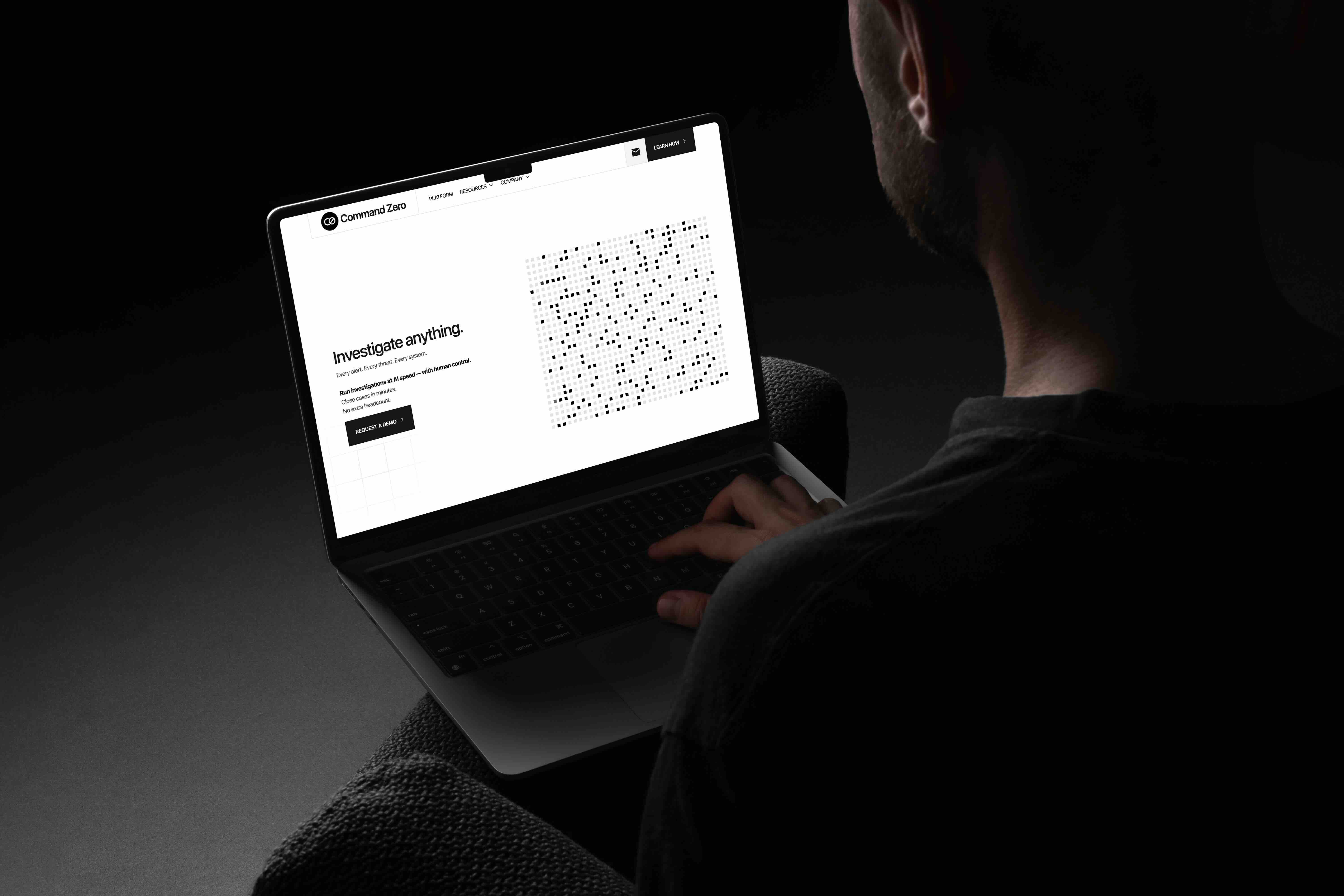 Person working on a laptop showing the Command Zero Investigate anything site in a dark room