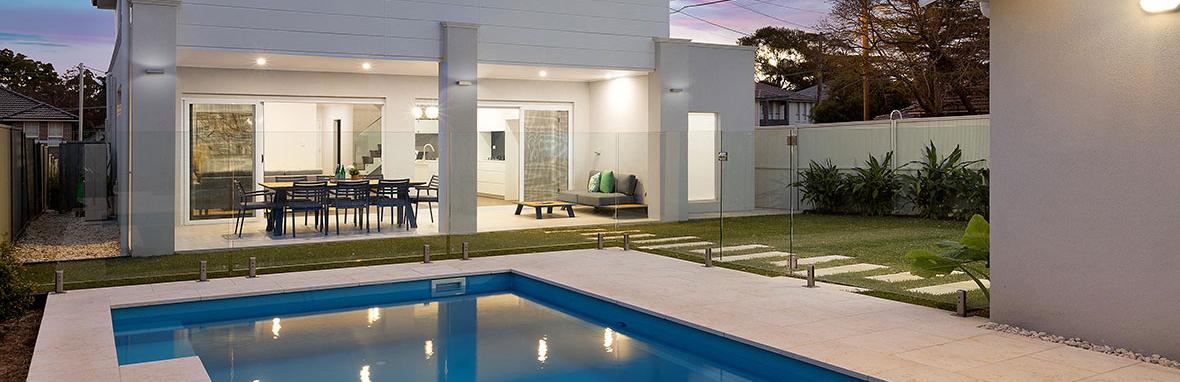 Modern Australian living area opening onto an alfresco entertaining space with large sliding doors and warm evening lighting