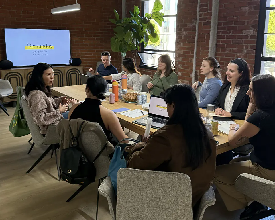 Dreamday team having a meeting around a wooden table in a modern brick office.
