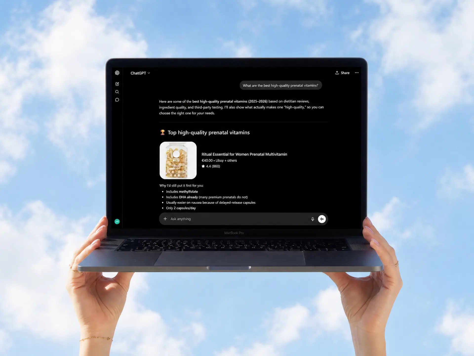Hands holding a laptop against a blue sky background displaying a ChatGPT screen with information about top high-quality prenatal vitamins.