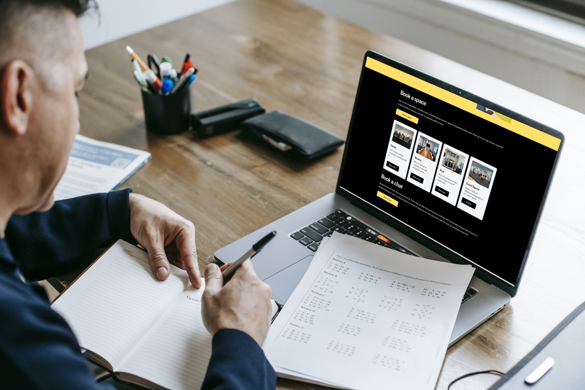 Barossa Regional University Campus website on laptop screen on a desk with a student and papers.