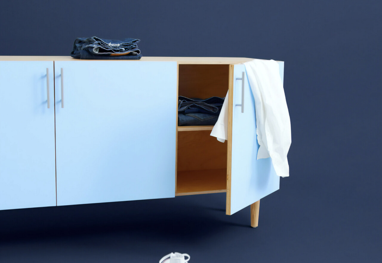 Light blue cabinet with an open door revealing folded jeans inside and a white shirt hanging on the door handle.