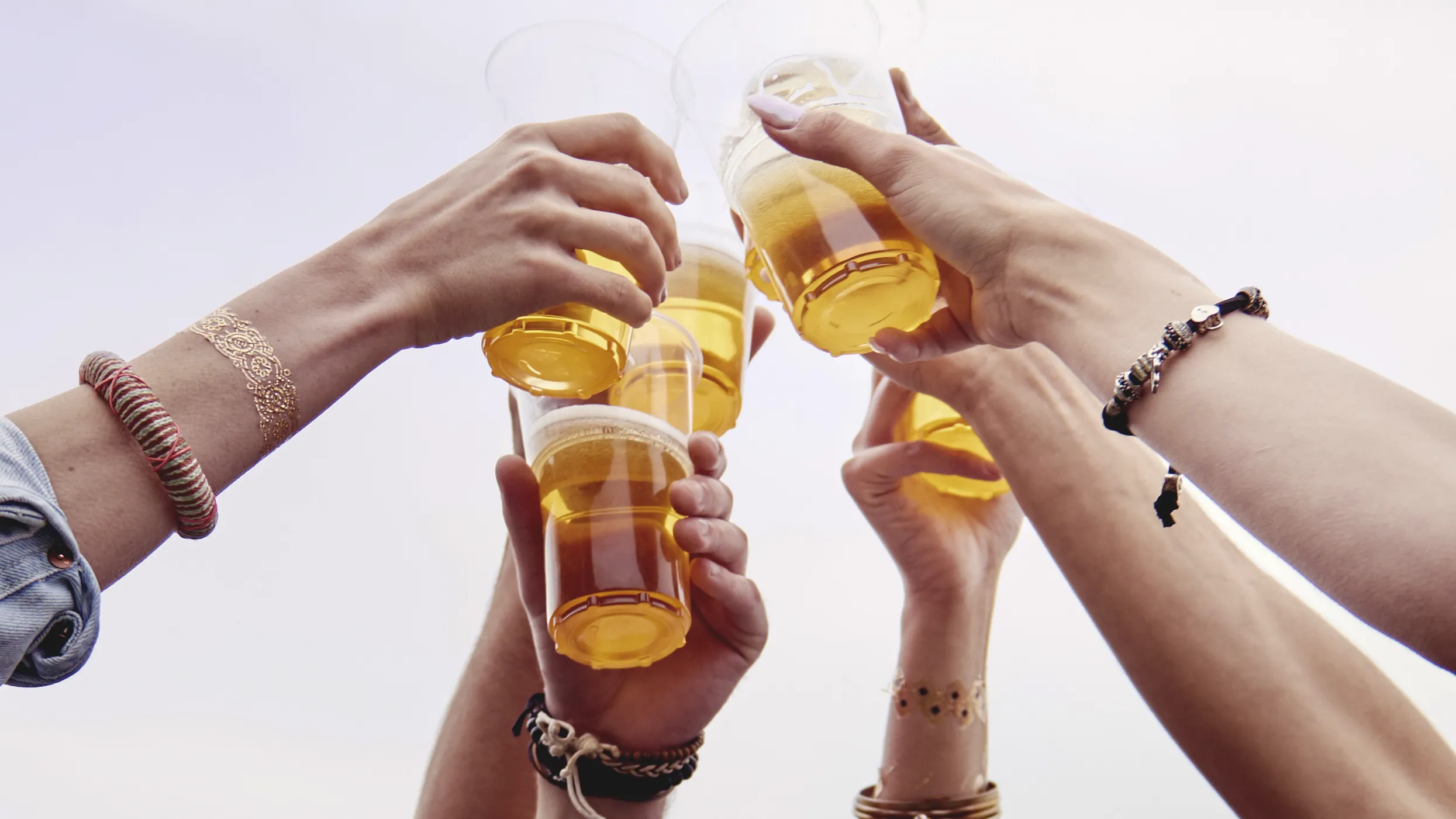 Hands in the air holding cups filled with drinks