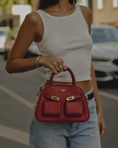 Woman on a street holding a dark red handbag