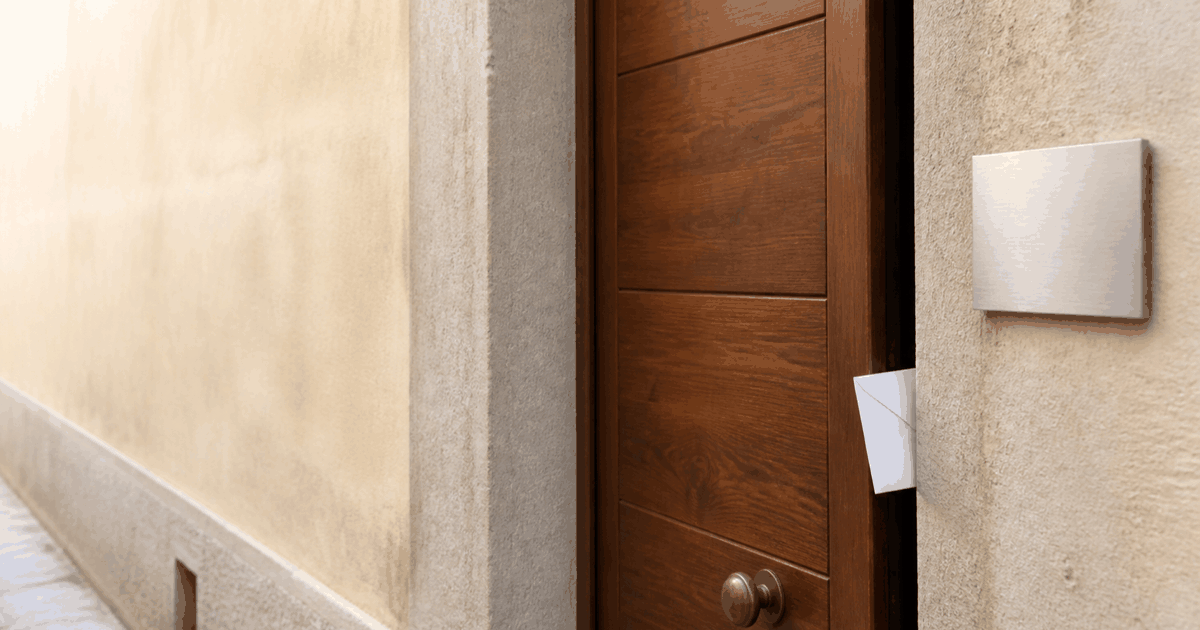 Porta d'ingresso di un appartamento con targa metallica senza codice e busta bianca infilata nella fessura