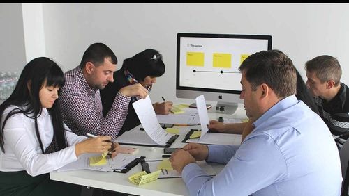 A group of people sitting around a table conducting a design thinking exercise