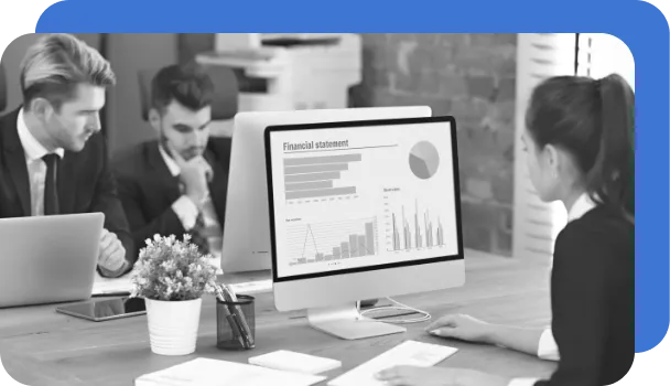 Office workers view financial statement analysis created by RPA on desktop computers.