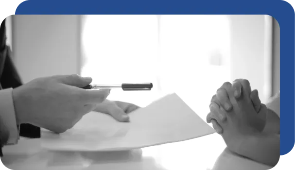 A banker hands documents to a client for signature.