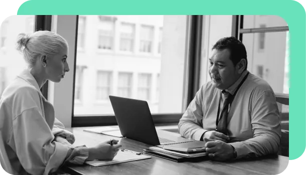 A bank employee reviews utility bills and other documents with a potential customer.