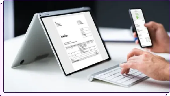A workspace with a tablet displaying an invoice, a smartphone, and a keyboard. A person is using the smartphone, representing digital financial management or document review.