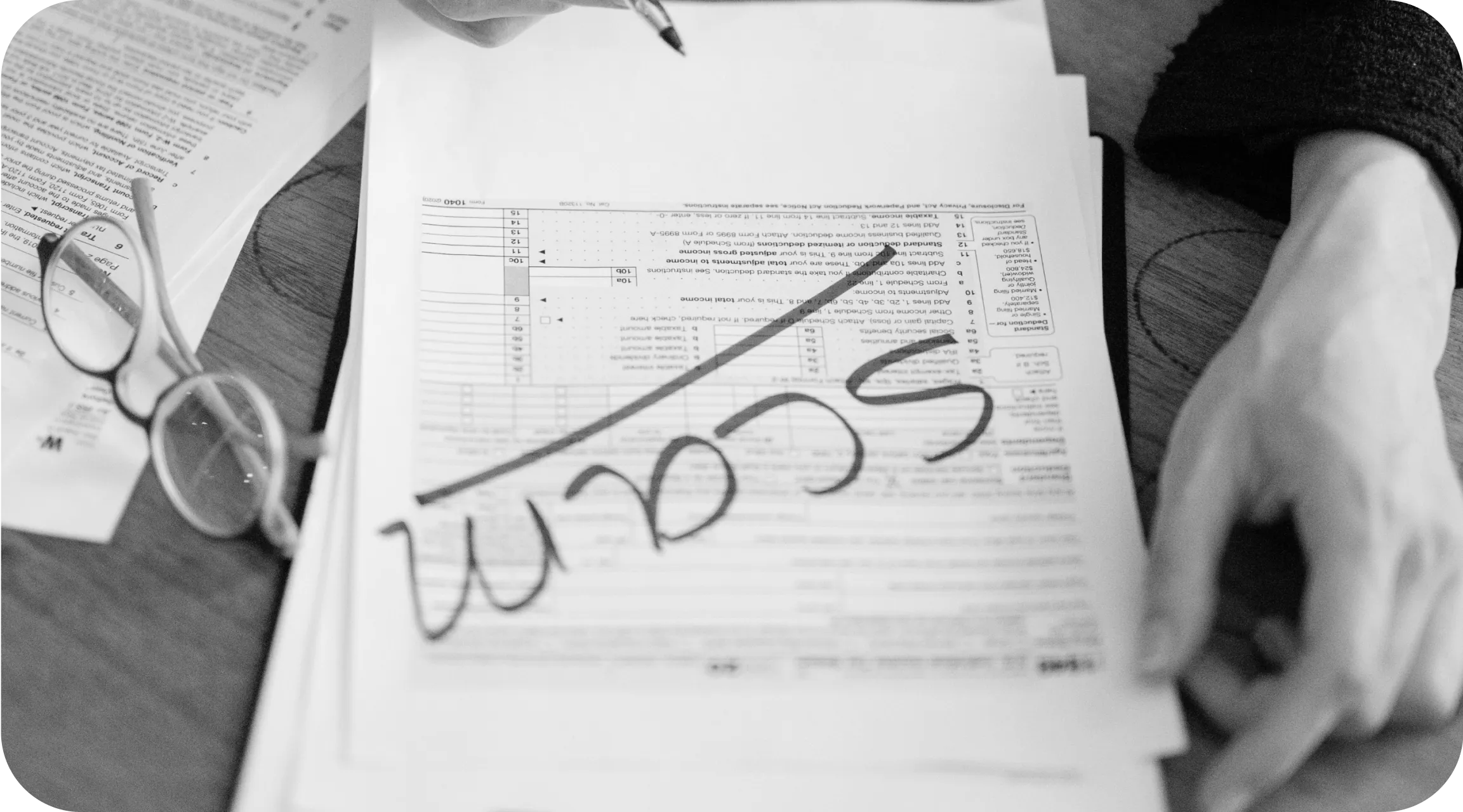 A close-up of a tax form marked with the word “SCAM” in large handwritten letters, surrounded by reading glasses and additional paperwork on a wooden desk, symbolizing document fraud.