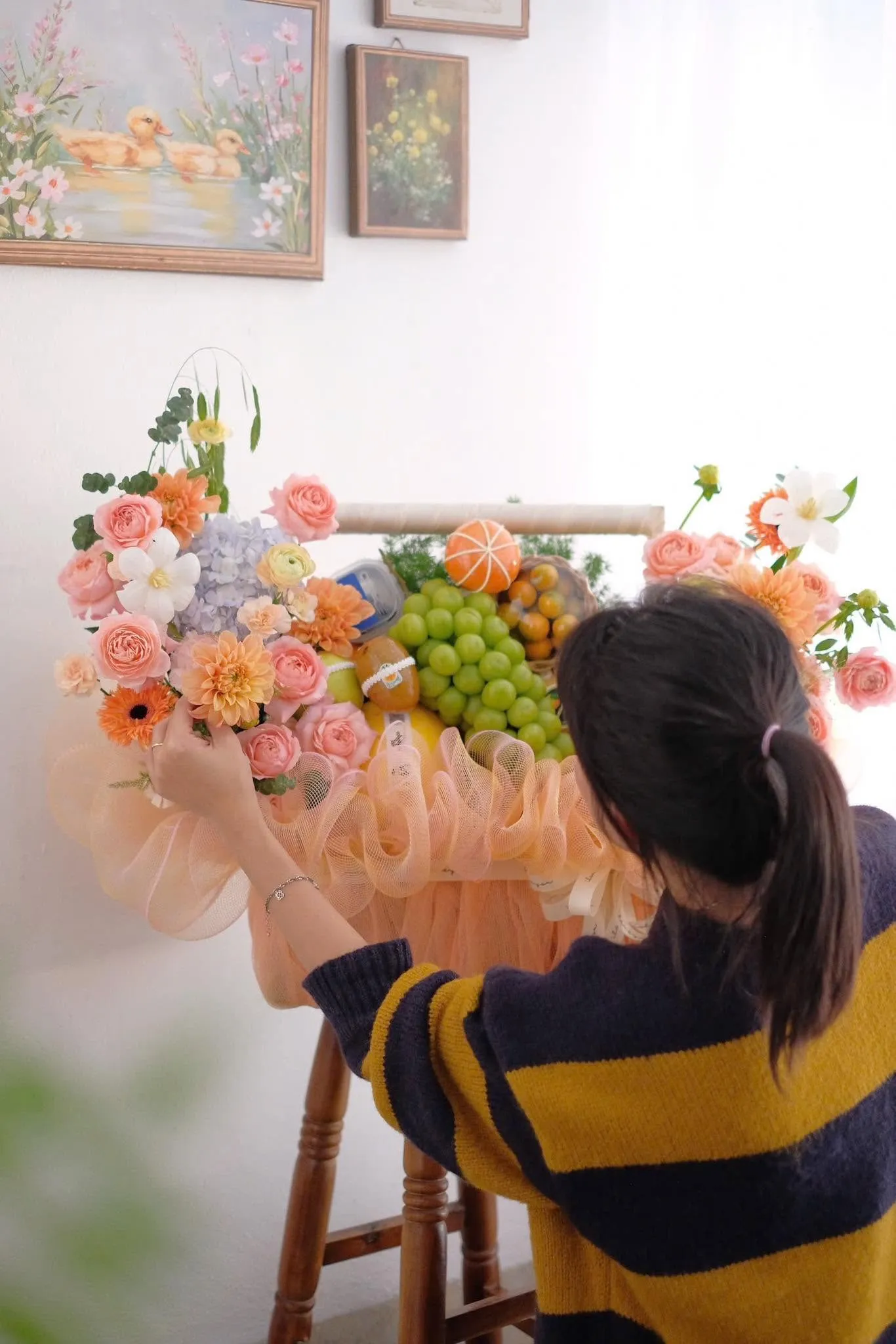 Cô gái đang cắm hoa hồng và trái cây lên giỏ quà trong nhà — King Fruit Thủ Dầu Một, Bình Dương