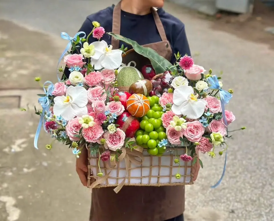 Người cầm giỏ hoa quả nho xanh, cam, hoa lan trắng và hoa hồng ngoài đường — King Fruit quận 11 HCM