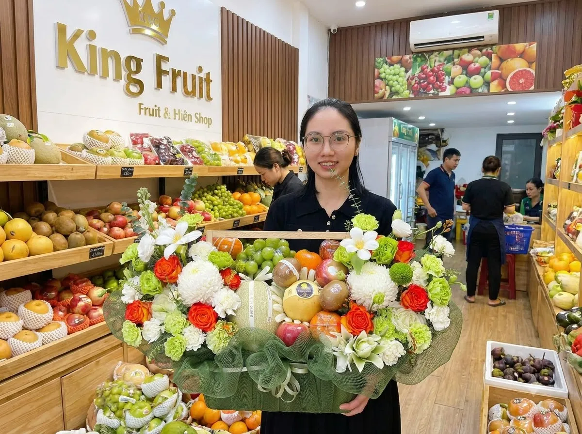Nhân viên cầm giỏ hoa trái cây bọc lưới xanh trong cửa hàng King Fruit đông khách — King Fruit Bình Sơn Quảng Ngãi