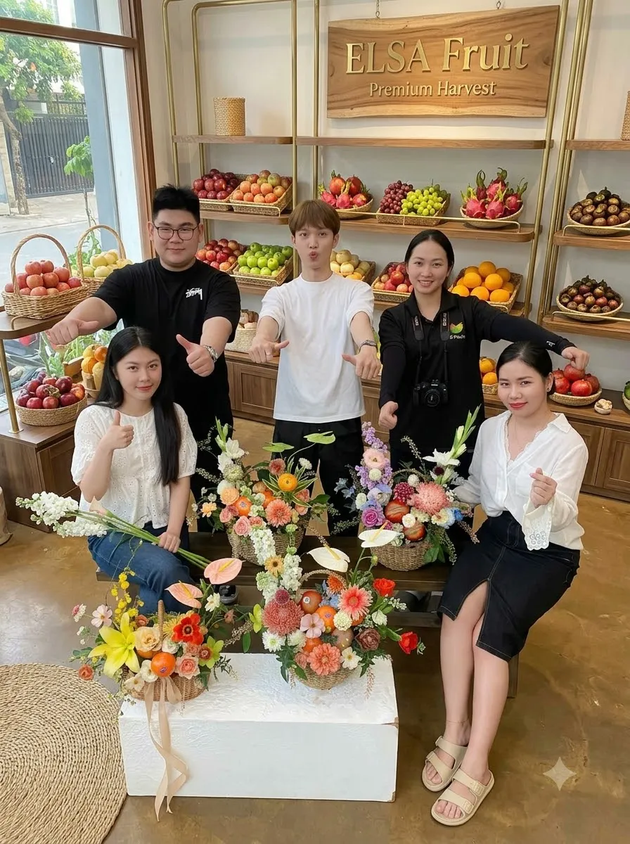 Nhóm nhân viên ELSA Fruit ngồi bên các giỏ hoa quả cắm hoa tươi trong cửa hàng — ELSA Fruit Ia Grai, Gia Lai