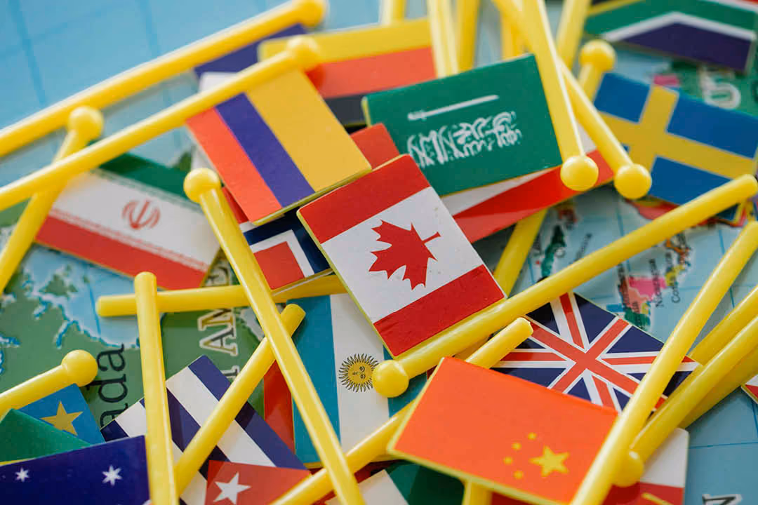 A pile of small flag pins on a world map.