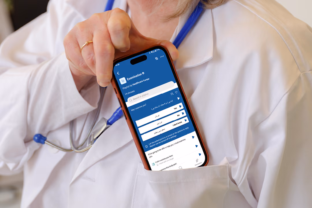 Person wearing a white medical coat and blue stethoscope holds a smartphone displaying the Care to Translate app with options for various symptoms and questions.