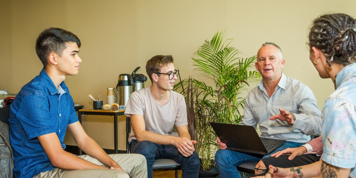 Three young adult males in group counseling with an adult therapist