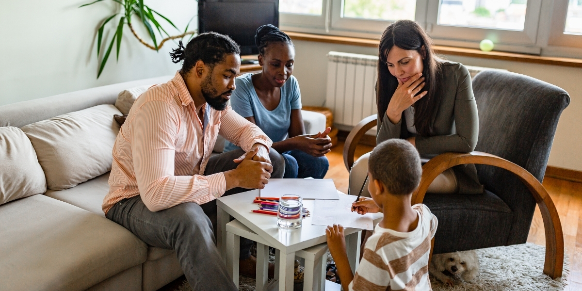 family around a table with a therapist at child therapy session