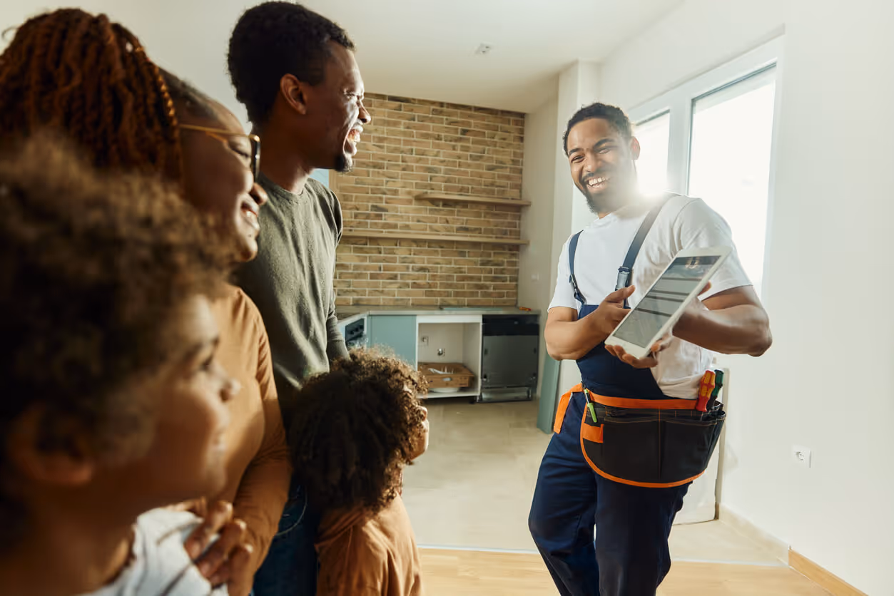 Happy contractor showing plans on touchpad to a family in moving house