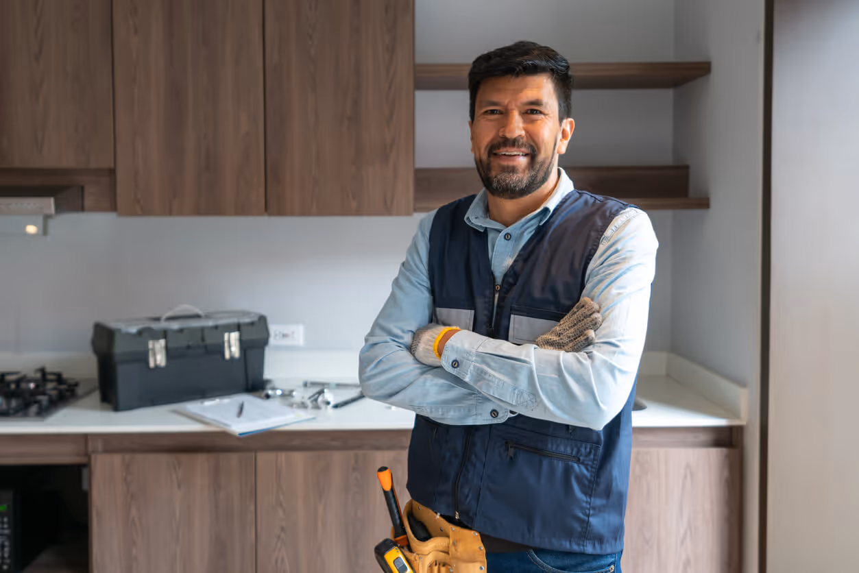 Happy plumber working at a house and smiling