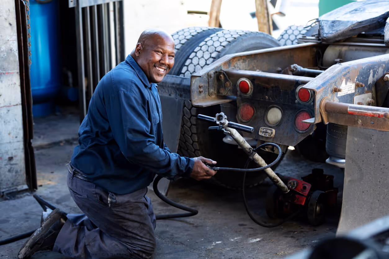 NH Garage Keepers Insurance concept - African-American man repairing semi-truck, using jack