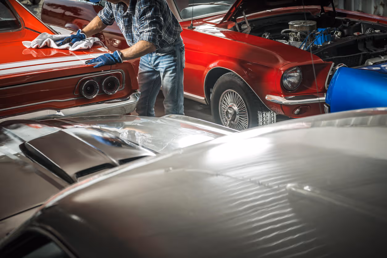NH Garage Keepers Insurance concept - man cleaning classic vehicles with rag in garage