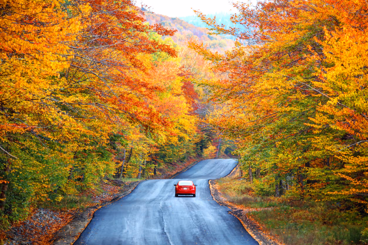 car driving in the fall in the White Mountains which are a mountain range covering about a quarter of the state of New Hampshire