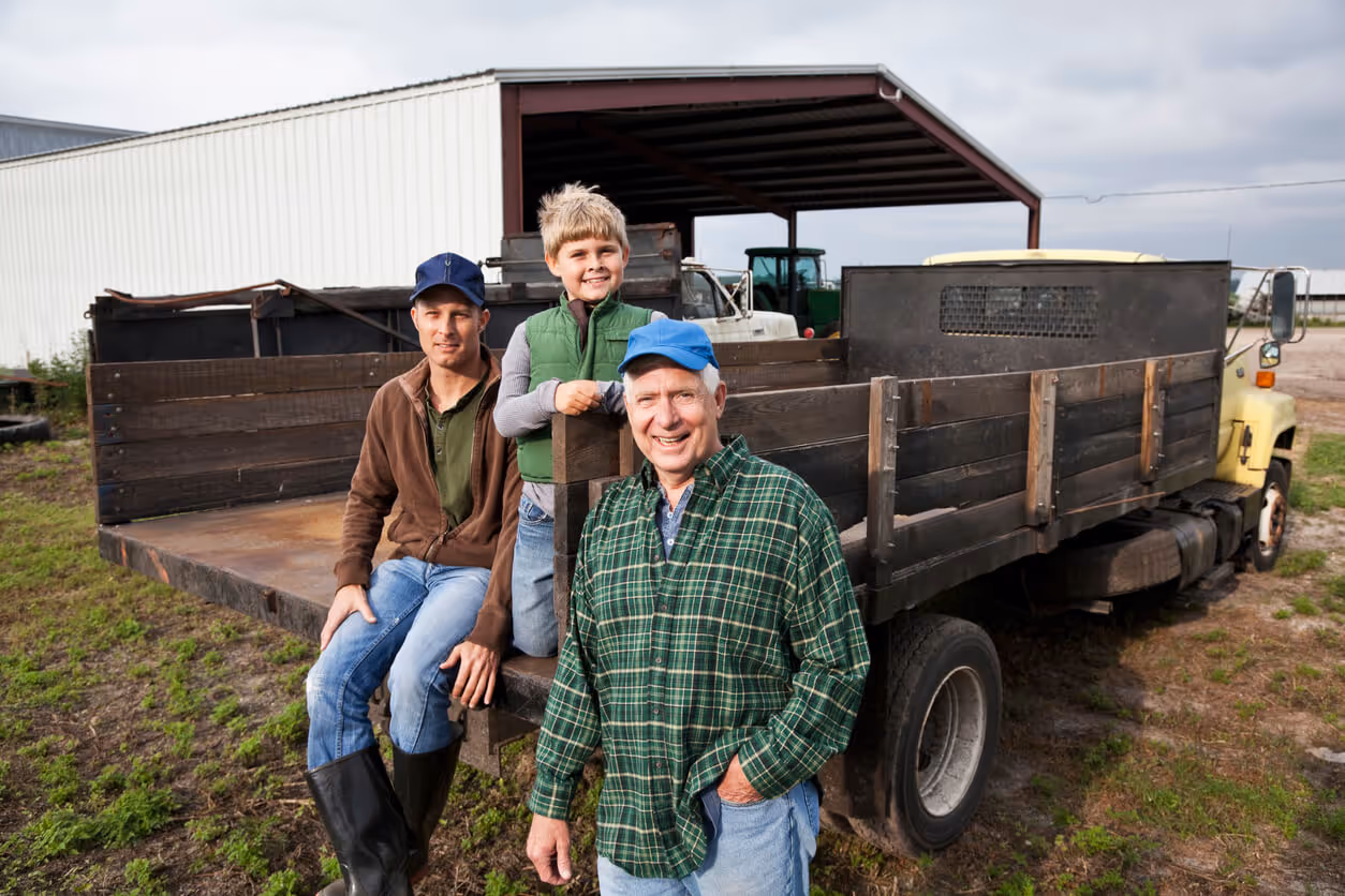 Three generations of men on the back of a truck on the family farm.