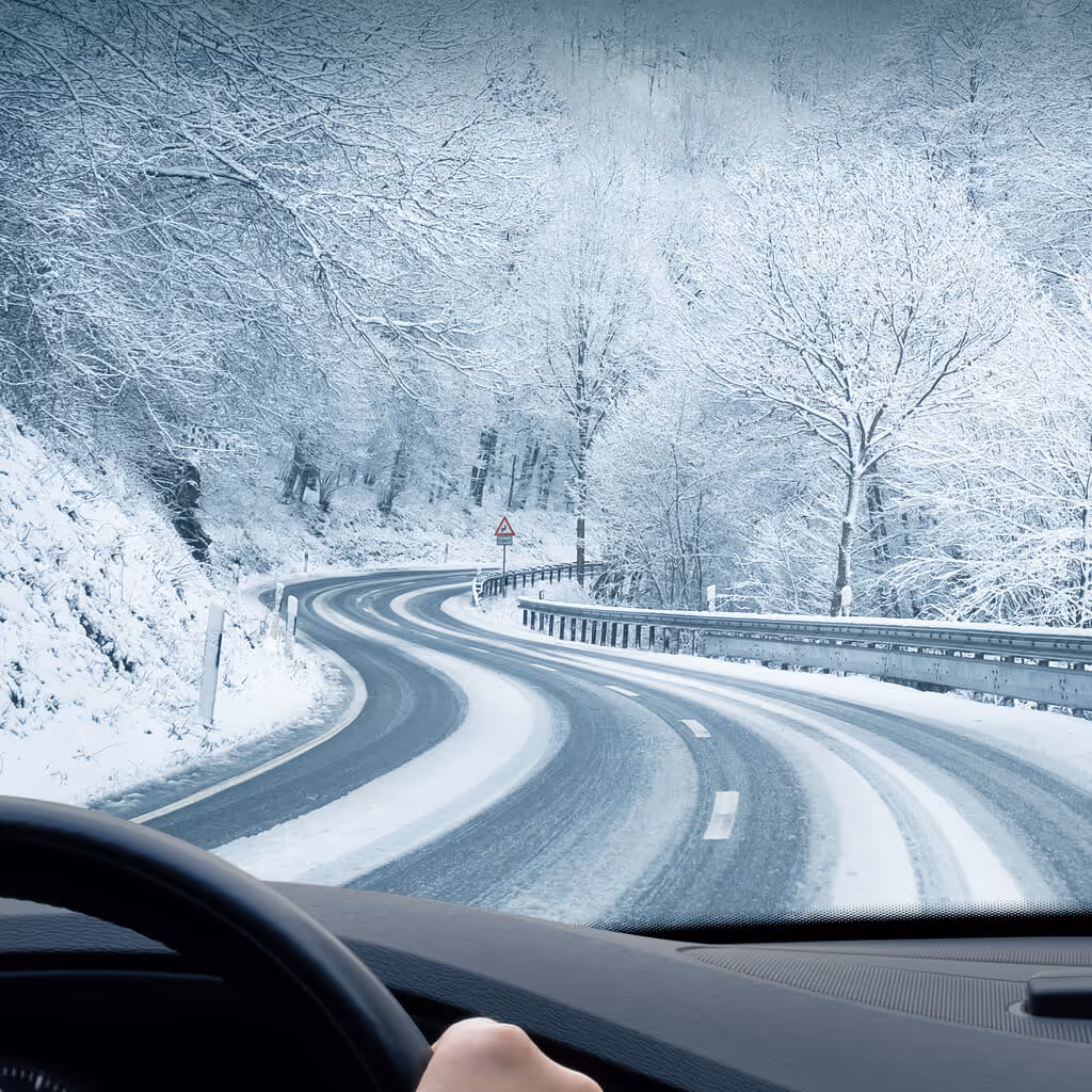 Curvy winter country road leading through a mountain landscape.